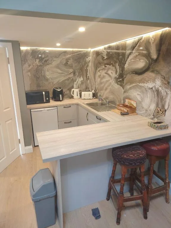 Kitchen with marble-effect splashback and breakfast bar with stools